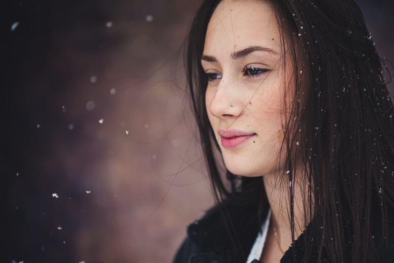 en svarthårig sorglig kvinna som står i snön