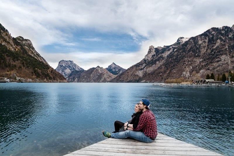 ett älskande par i en omfamning som sitter på en brygga vid sjön