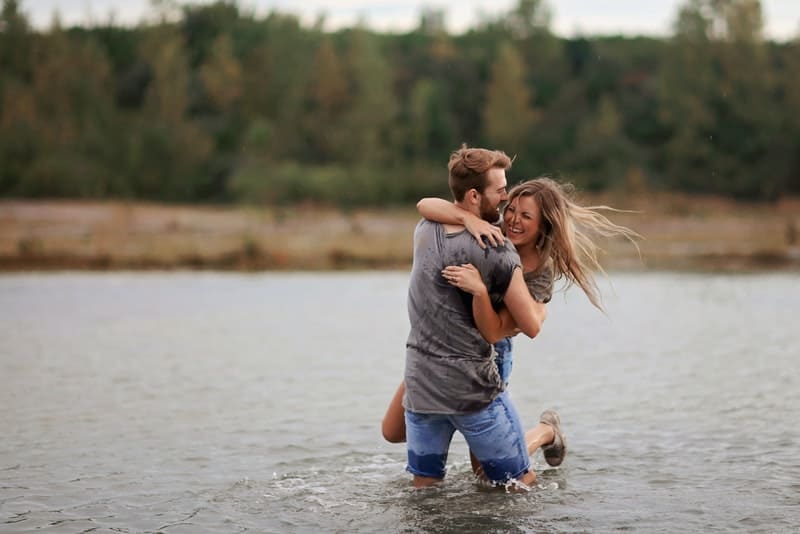 ett leende älskande par som står i en omfamning i floden