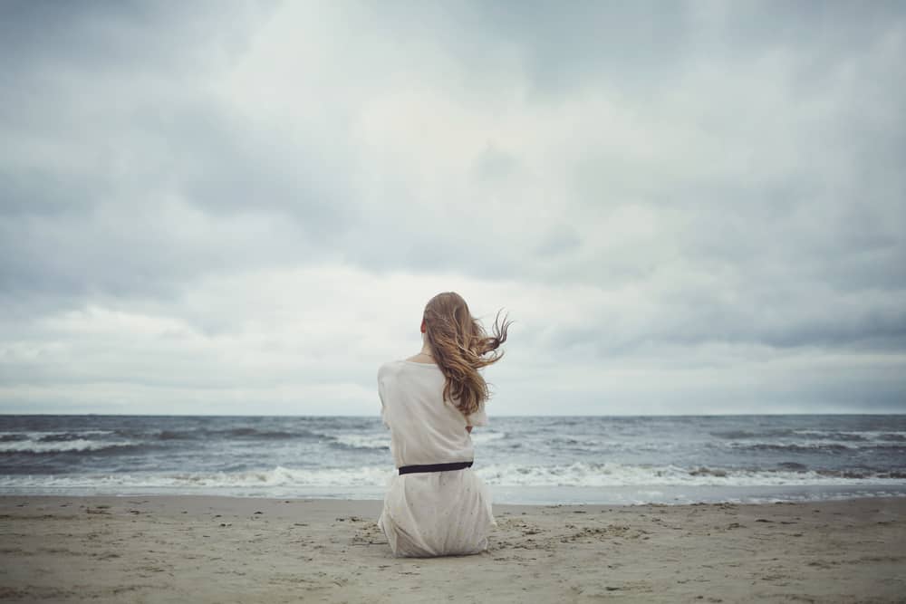 flicka sitter ensam på stranden