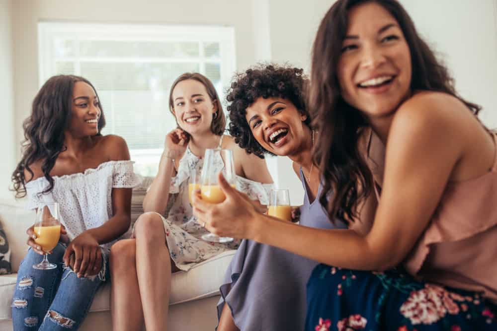 grupp kvinnliga vänner som tycker om på en fest och skrattar