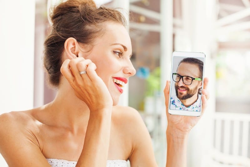 vacker ung kvinna chattar online med pojkvän på sin telefon