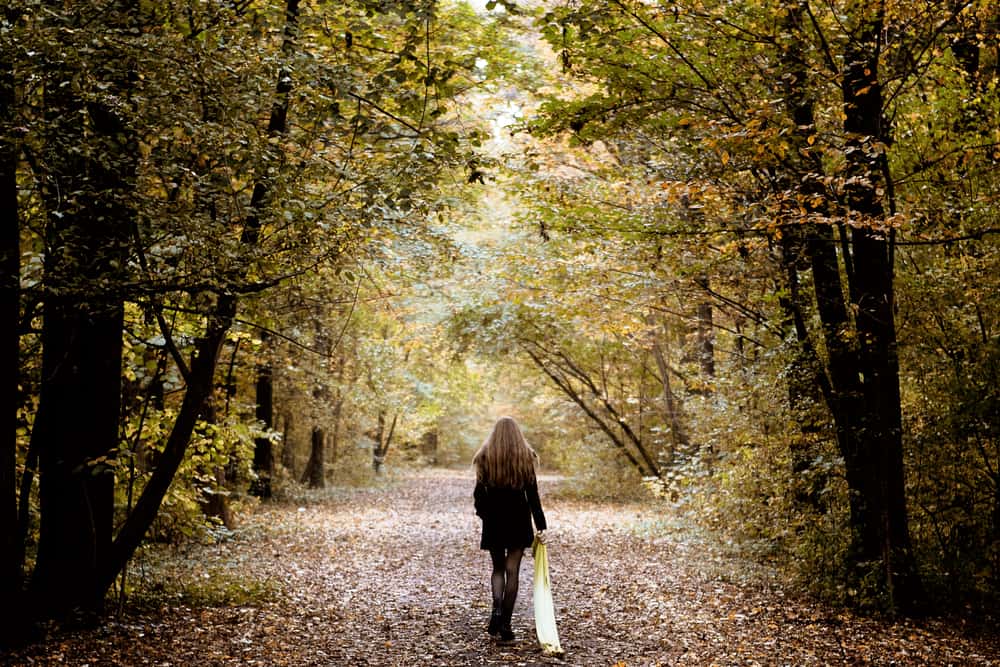 kvinna med halsduk som går ensam i skogen