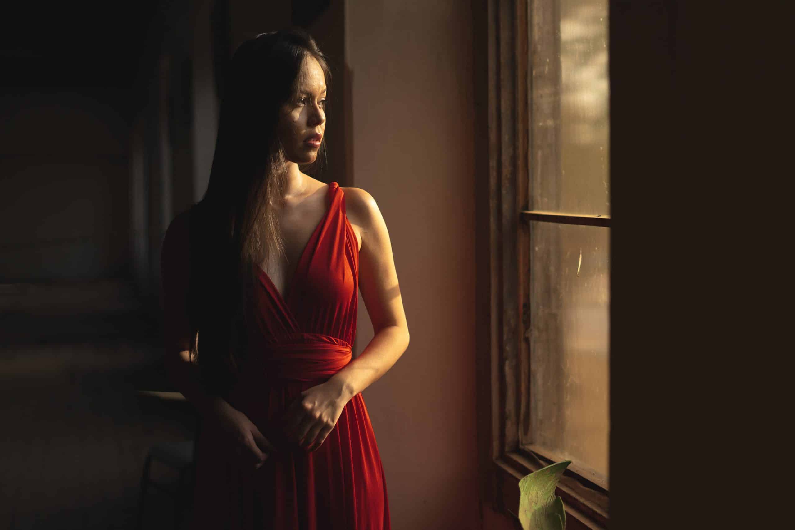 kvinna med röd klänning som står nära fönstret