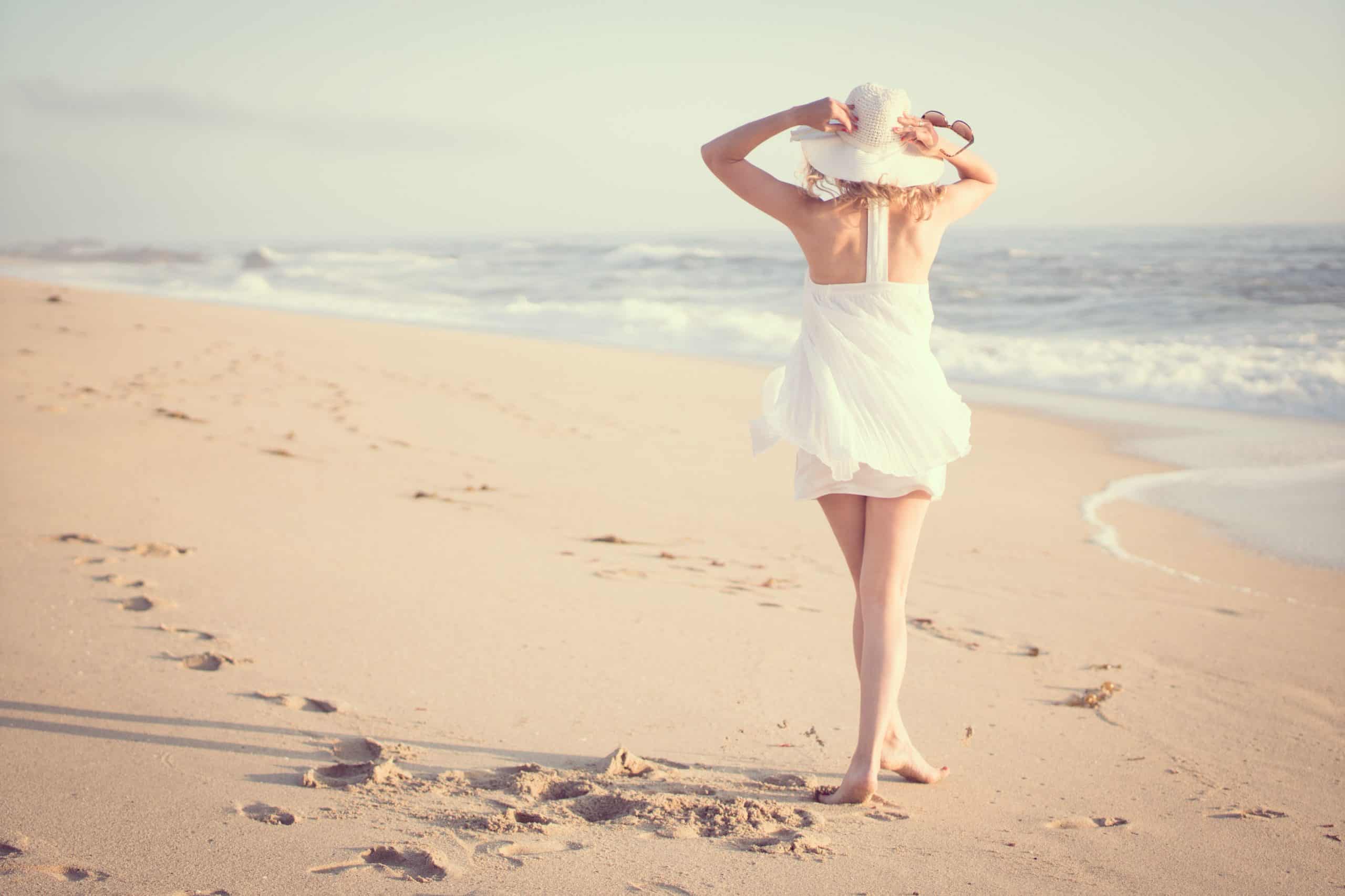 kvinna med vit hatt ensam på stranden