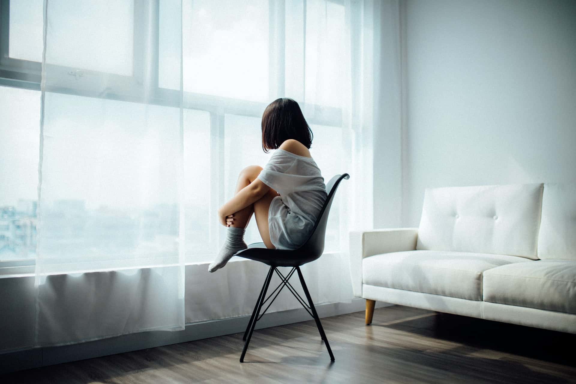 kvinna sitter nära fönstret på svart stol