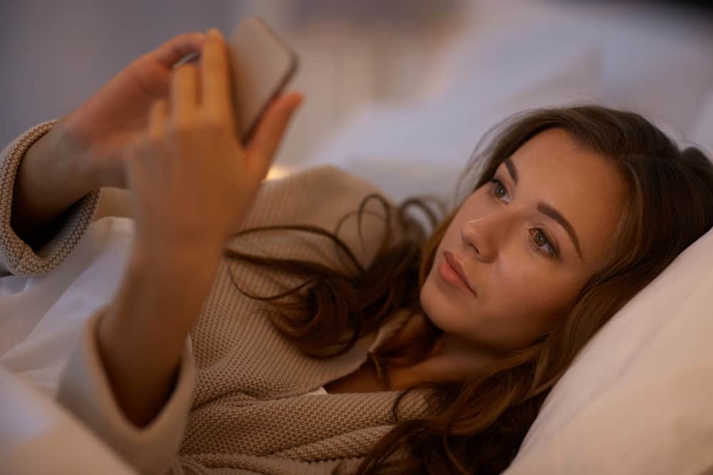 kvinna smsar på smarttelefonen i sängen hemma sovrum på natten