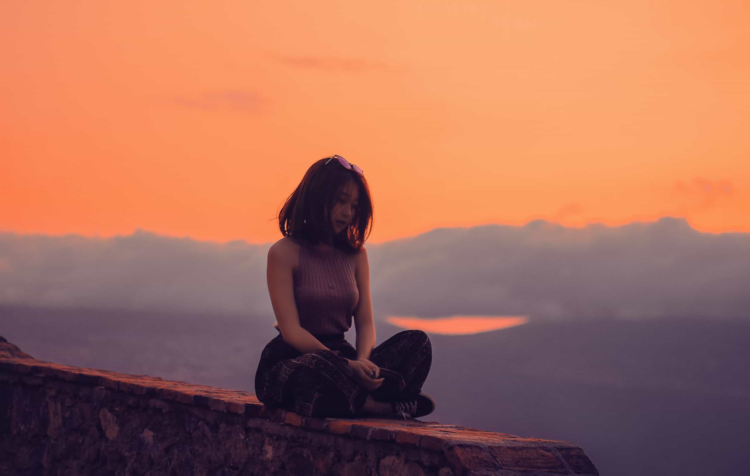kvinna som sitter på en klippa ensam