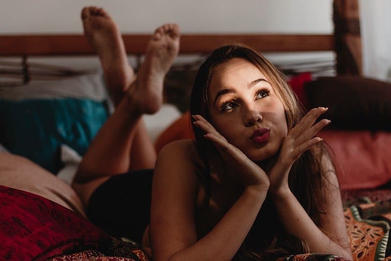 kvinnan som ligger på sängen med benen korsade skickar en kyss
