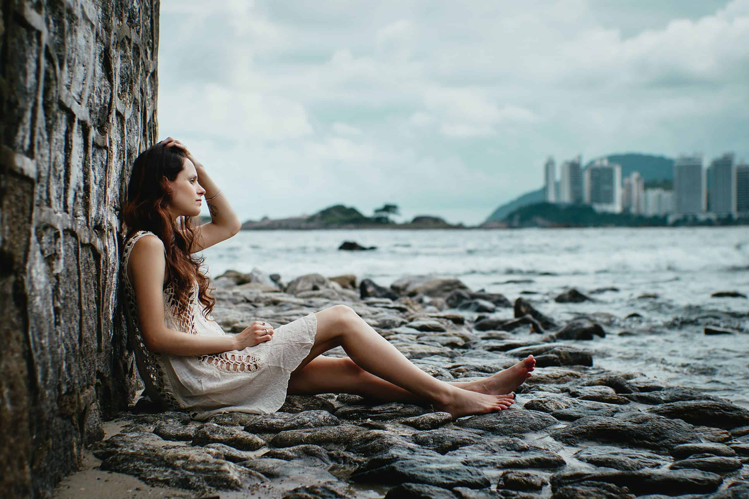 ledsen kvinna sitter ensam och tittar på havet