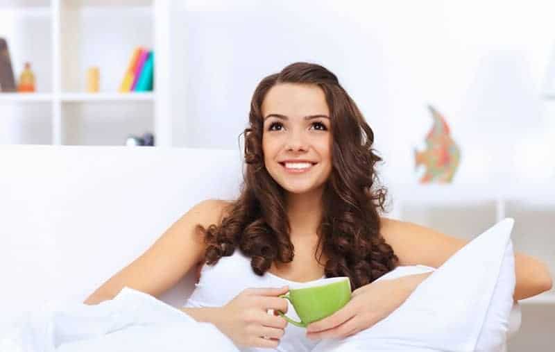 leende kvinna som dricker kaffe ensam