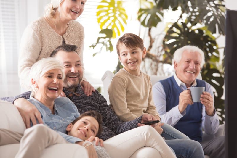 Lycklig familj tillbringar eftermiddagen tillsammans medan man tittar på TV