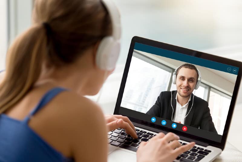 Man och kvinna i hörlurar som kommunicerar online via videosamtal
