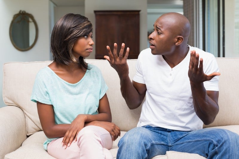 Olyckliga par som har ett argument på soffan hemma i vardagsrummet