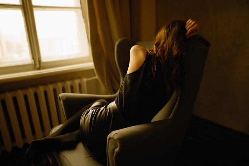 sorglig kvinna på soffan nära fönstret