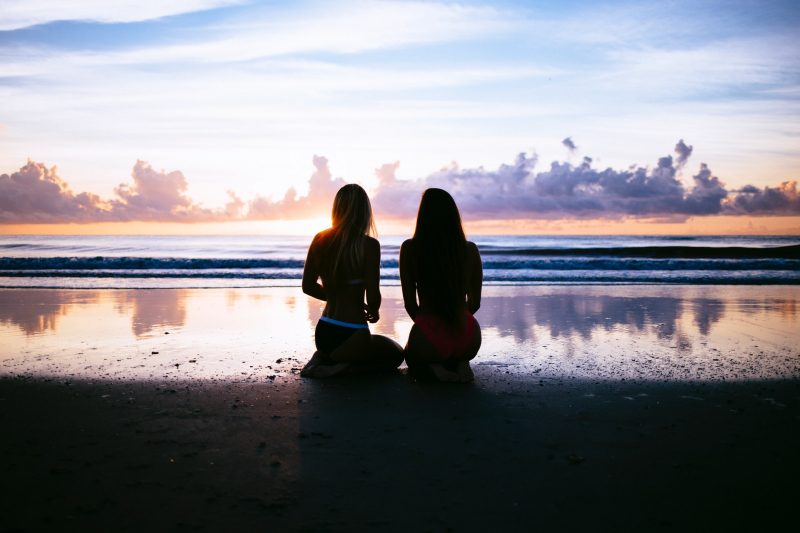 två kvinnor som sitter på stranden