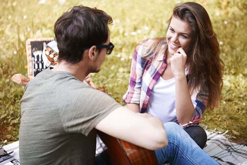 kvinna som ler till mannen som spelar gitarr