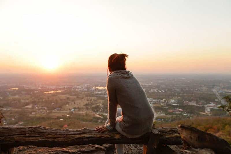 kvinna sitter ensam och tittar på solnedgången