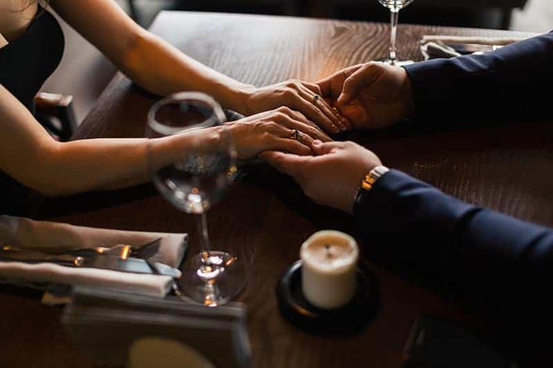 man och kvinna som håller händerna på bordet