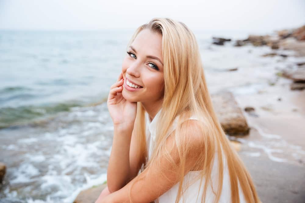 ung blond kvinna sitter nära havet