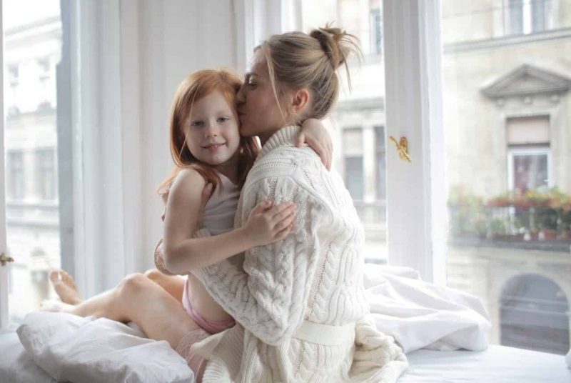kvinna kysser dotter i sängen