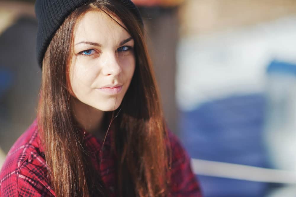porträtt av en vacker tonårig flicka med blå ögon som bär en röd skjorta och hatt