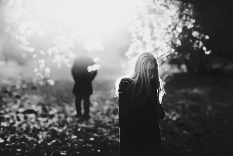 Ensam ledsen kvinna med blont hår som vandrar runt i parken