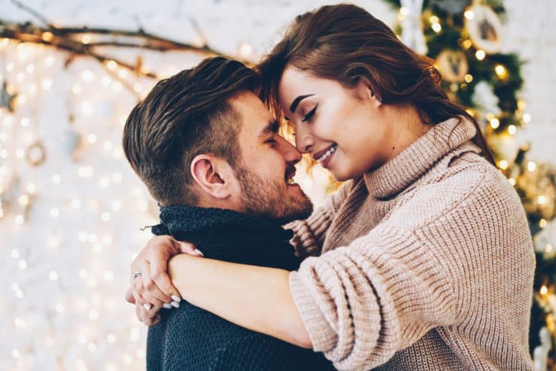 Förälskade romantiska par som känner sig glada över sin romantik som tillbringar julafton tillsammans