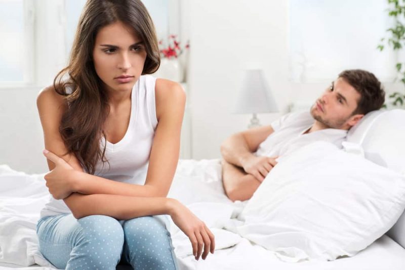kvinna som sitter på sängen missnöjd med mannen