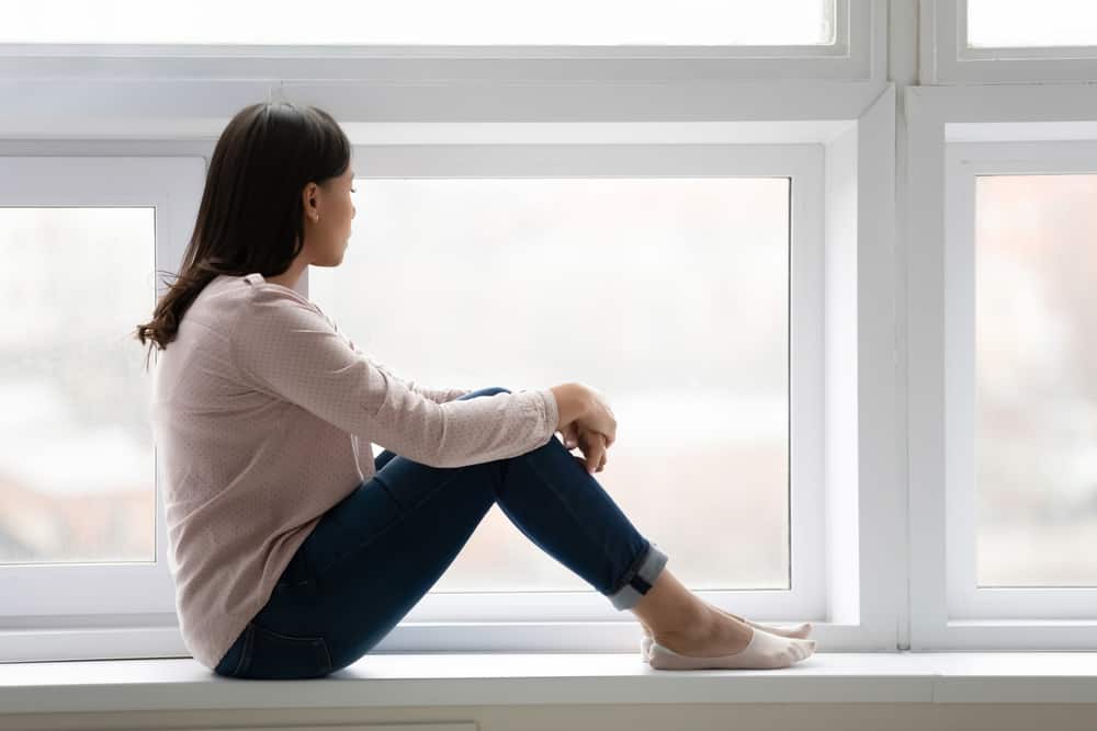 ensam kvinna som sitter vid fönstret