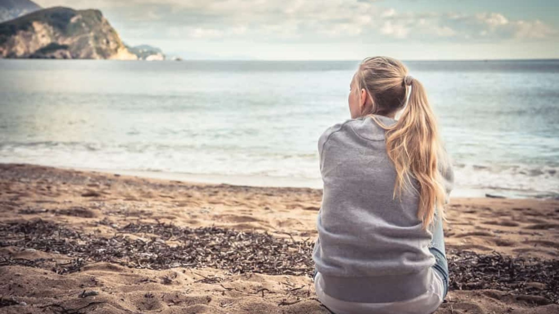 Eftertaenksamt ensamt sammanträde foer ung kvinna pae stranden