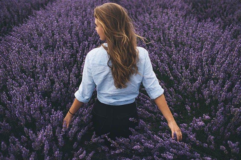 kvinna som står i fält av blommor