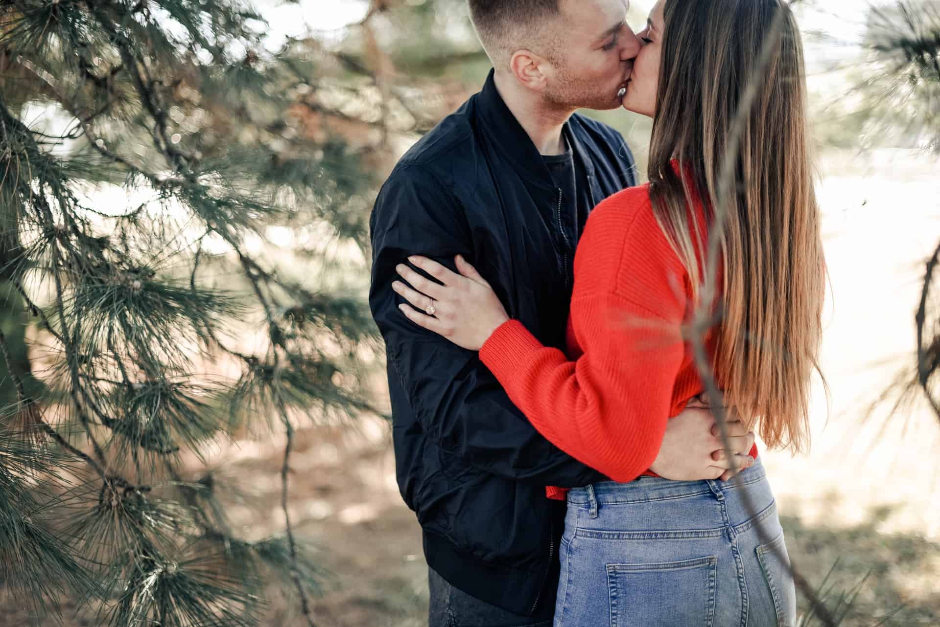 en man och en kvinna som kysser i skogen