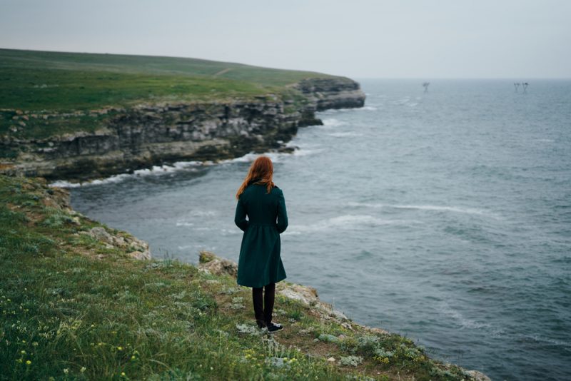 kvinna som står med ryggen och tittar på havet