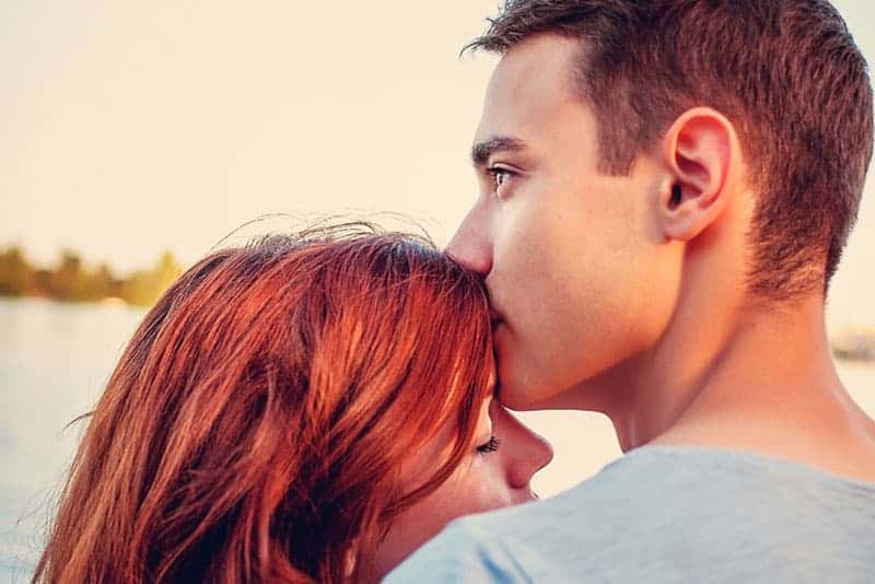 man kysser rödhårig kvinna i pannan