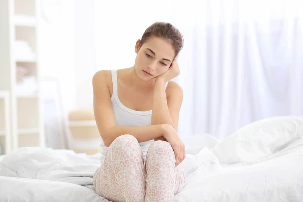 Deprimerat sammanträde för ung kvinna på säng hemma