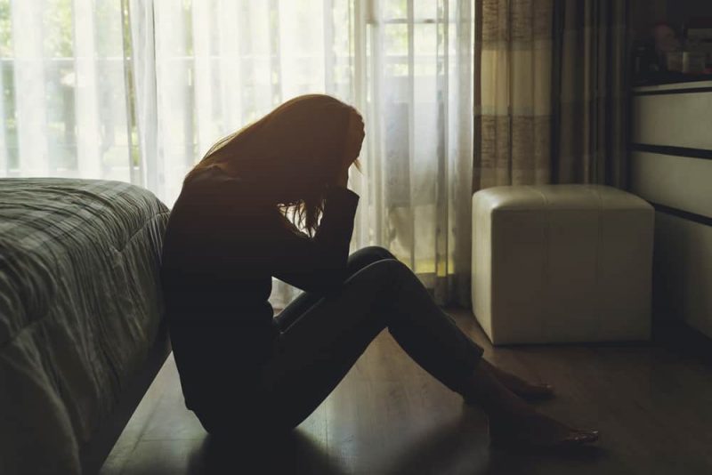 Ensam ung kvinna som känner sig deprimerad och stressad sittande