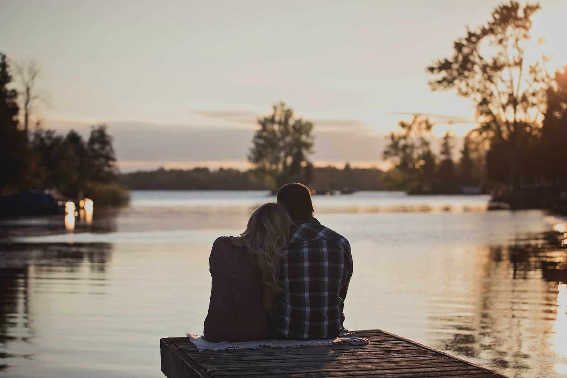 man och kvinna sitter på bryggan nära sjön