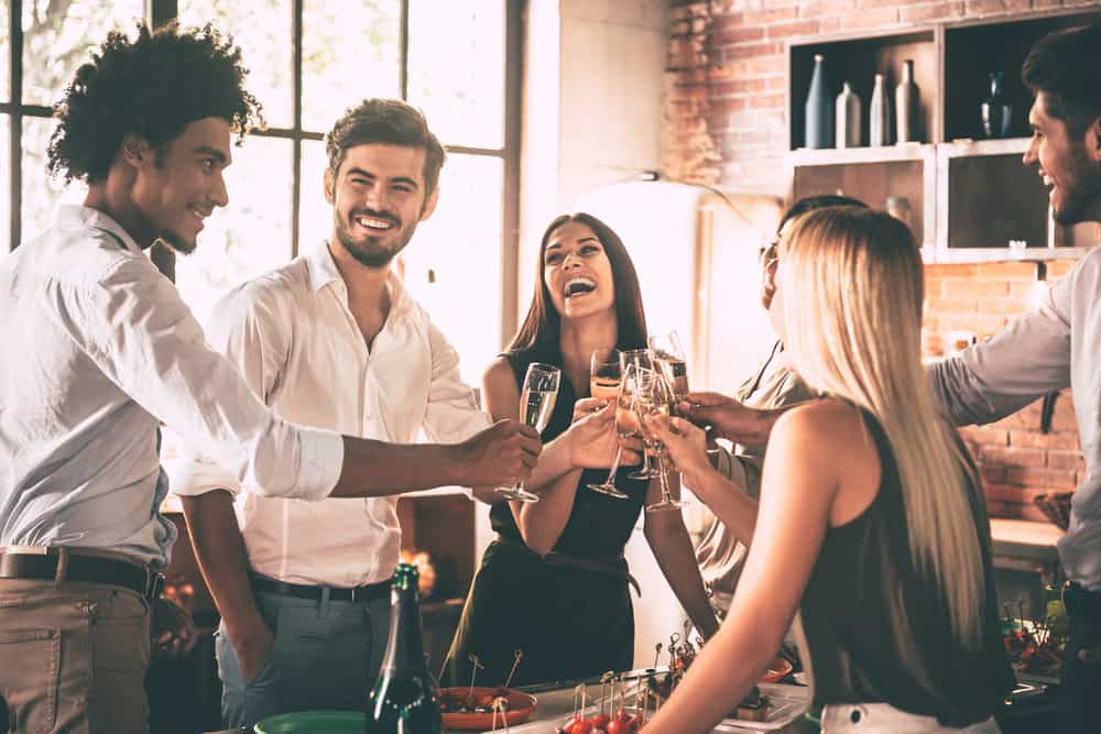 Glada unga människor som hejar med champagneflöjt