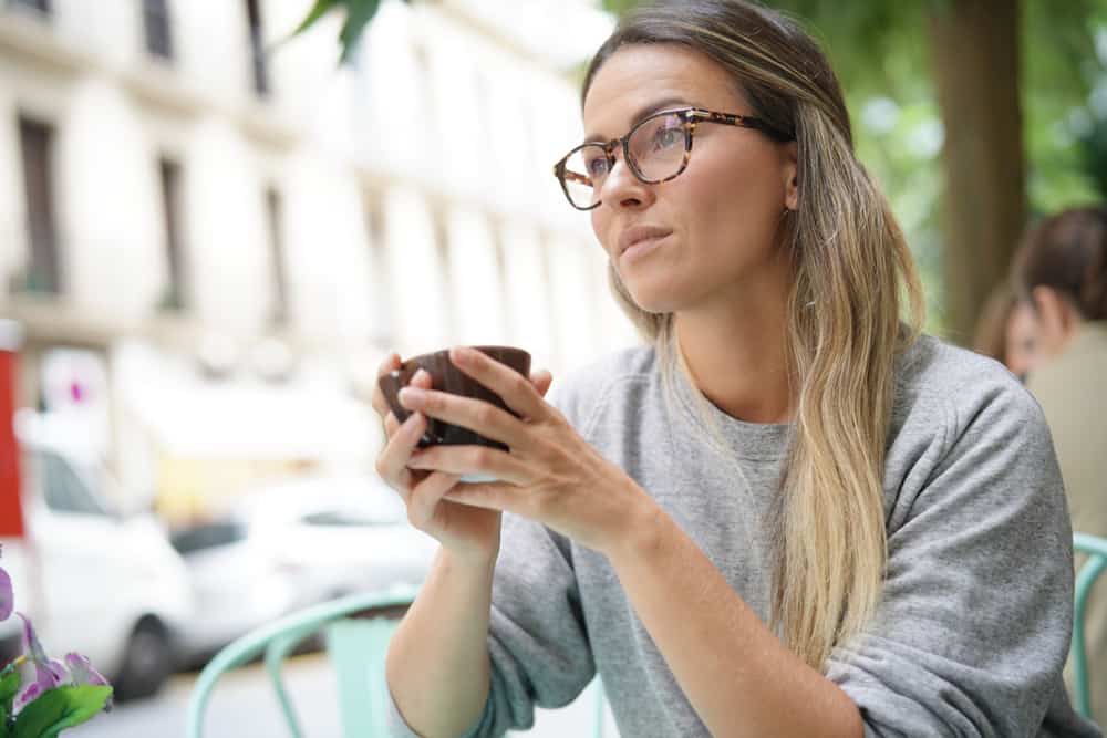 blond kvinna som bär glasögon som sitter och dricker kaffe