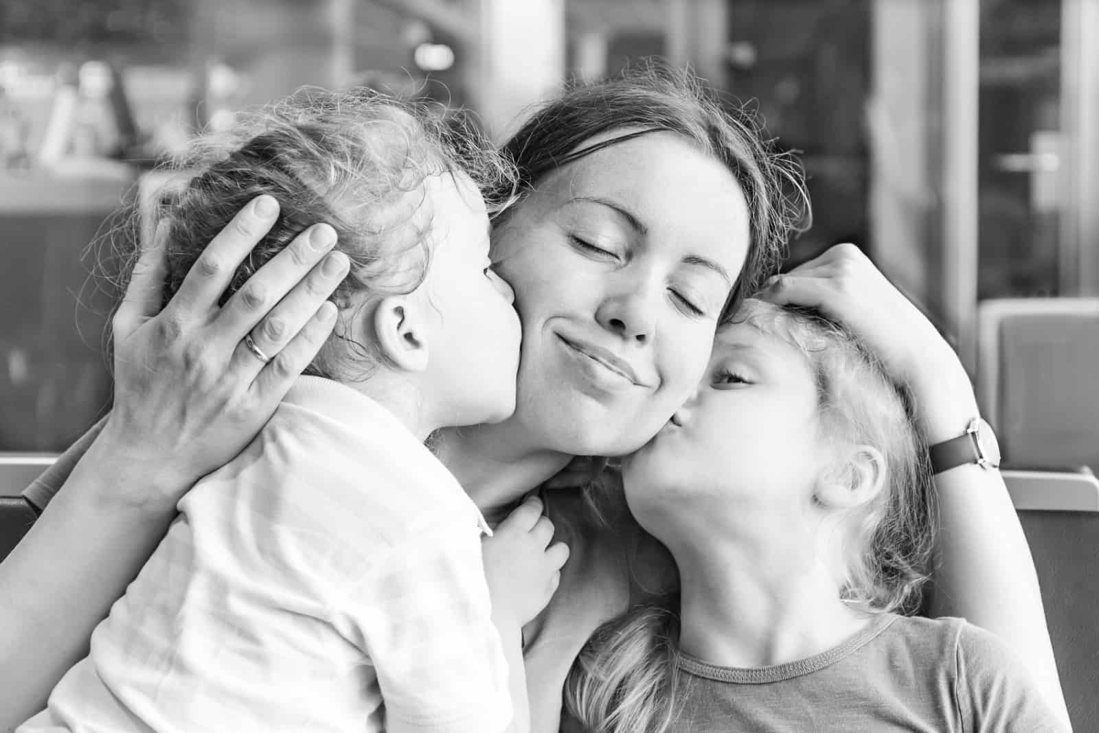döttrar som kysser sin lyckliga mamma