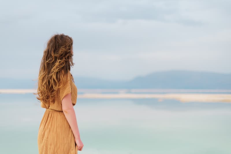 en flicka med långt hår står vid havet