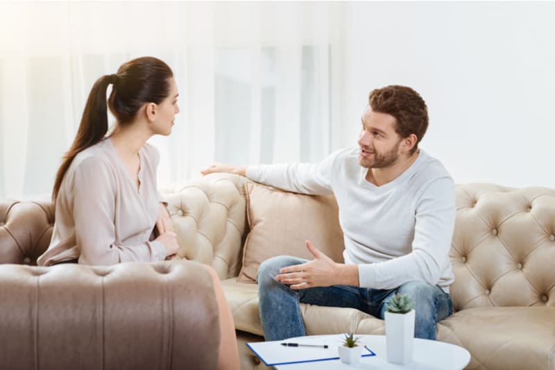en man och en kvinna sitter i soffan och pratar