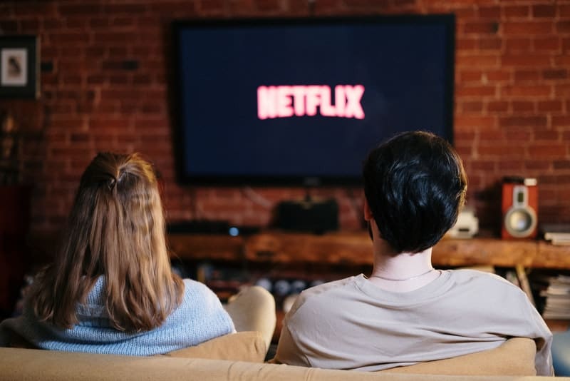 en man och en kvinna som sitter på en soffa och tittar på en film på Netflix