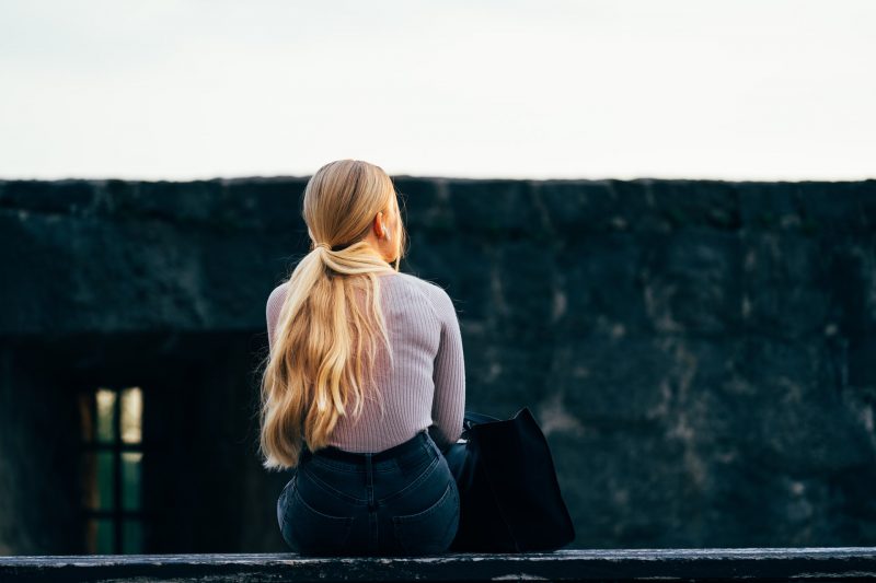 kvinna med långt blont hår som sitter ensam