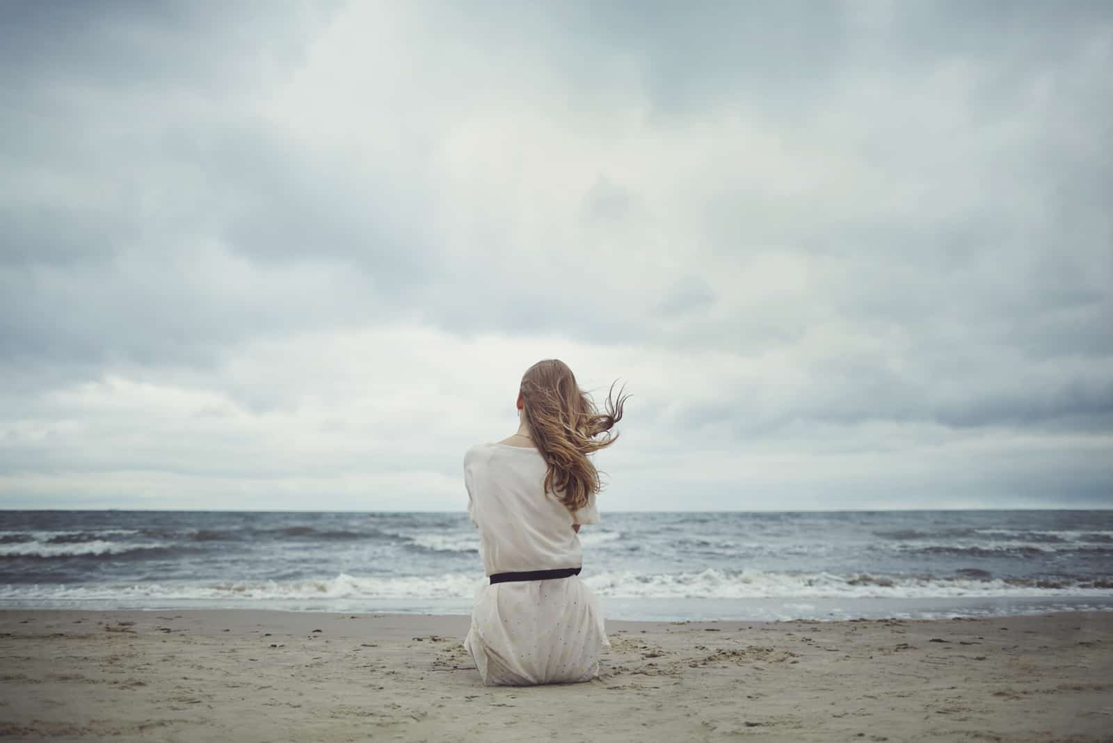 kvinna som sitter på stranden ensam