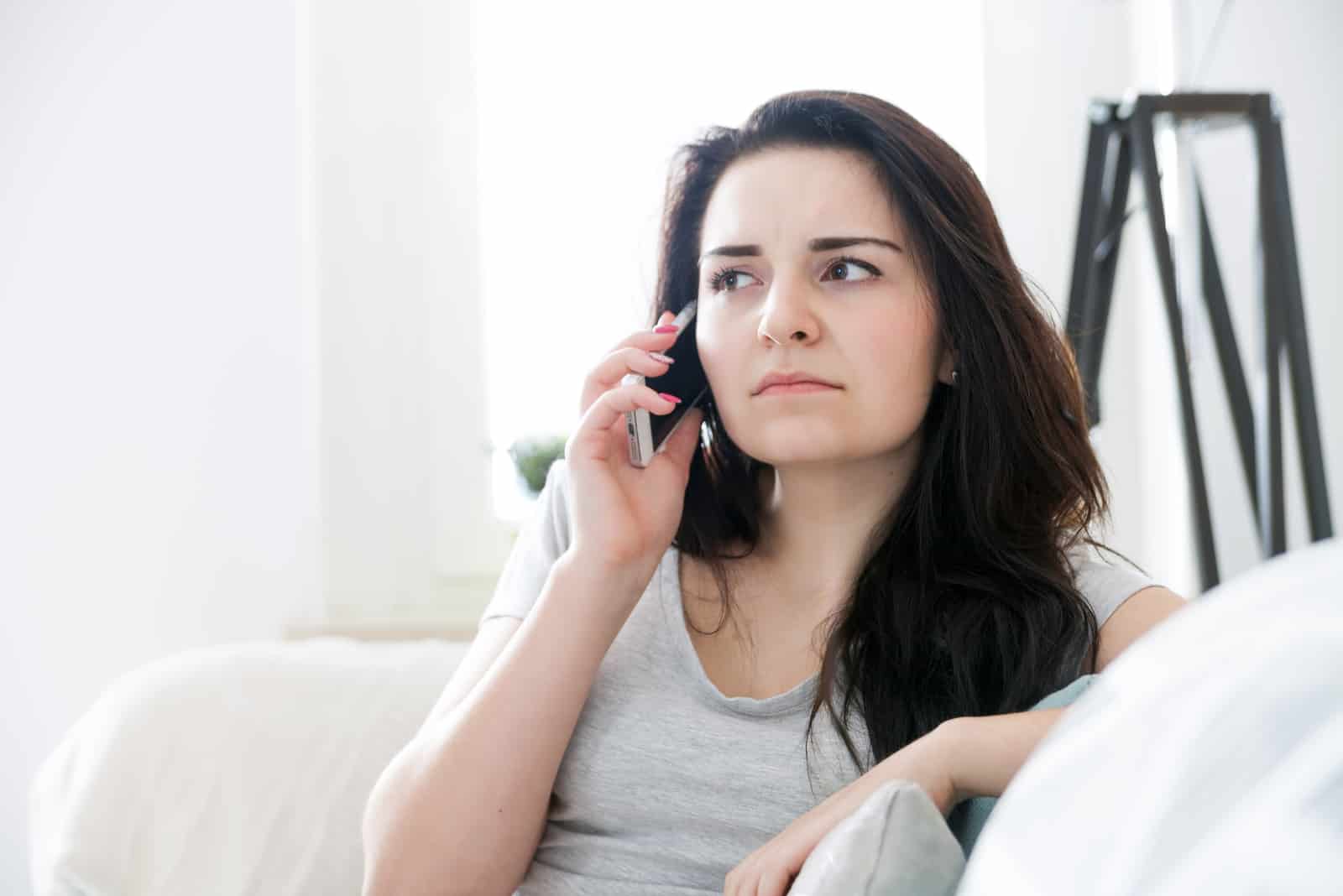 orolig kvinna som talar i telefon medan hon sitter på soffan