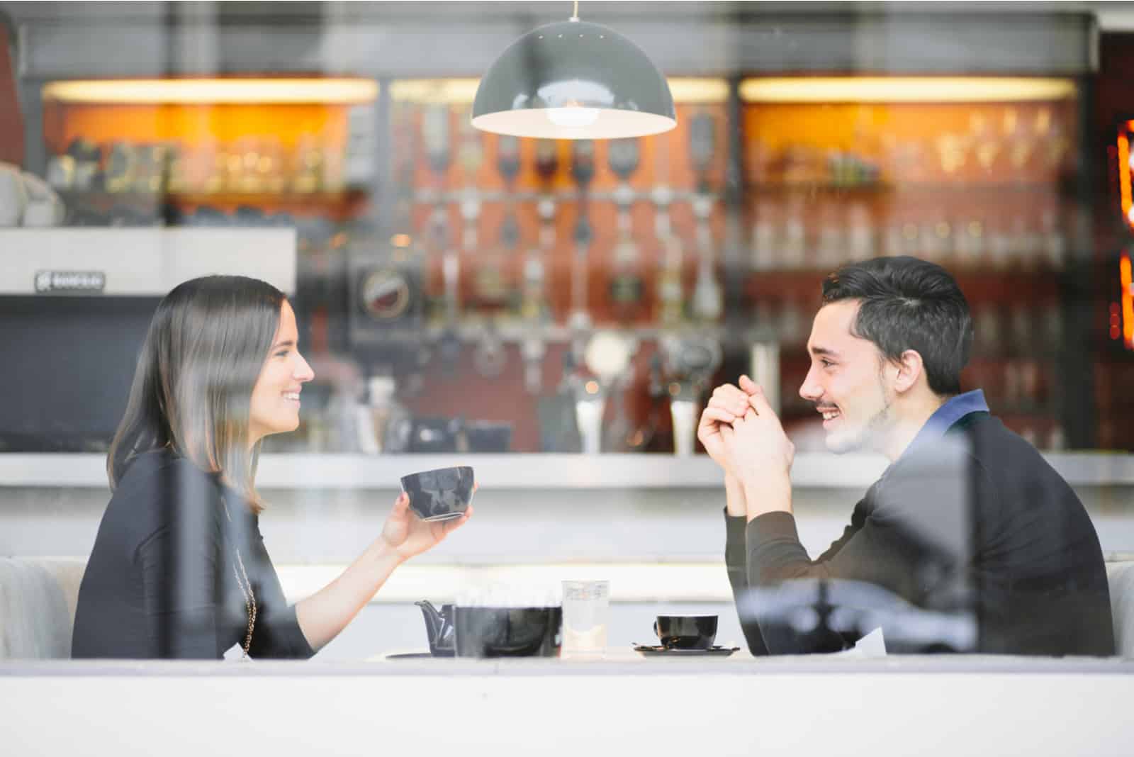 couple drinking coffee laughing in cafe