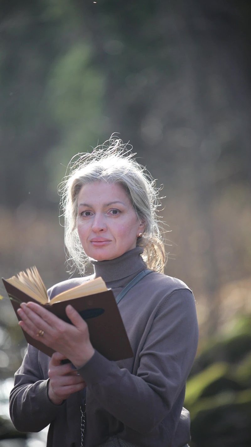 A woman reading a book in the woods
