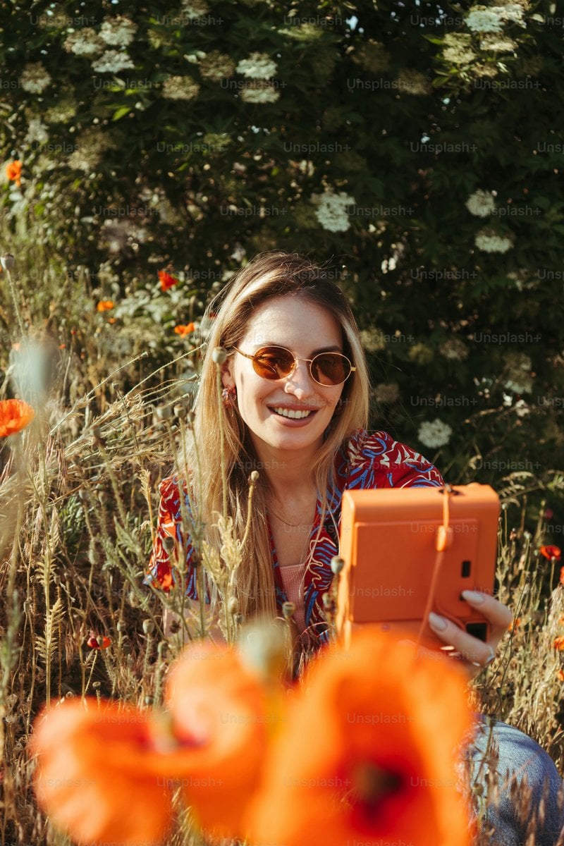 A woman sitting in a field with an orange tablet photo ...